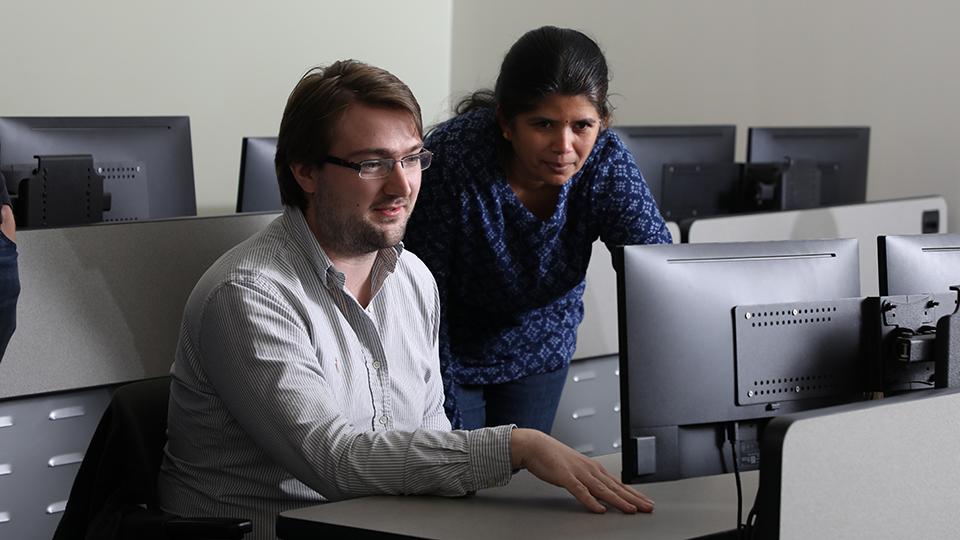 A student and instructor working together on a computer.